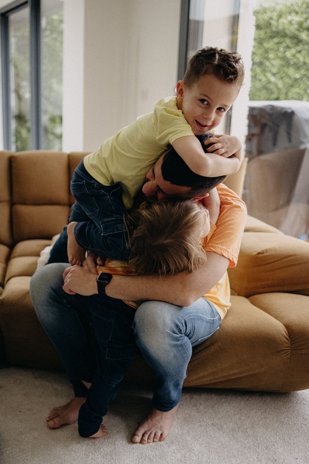Playful moment on a beige couch as parent and child roughhouse together at home.