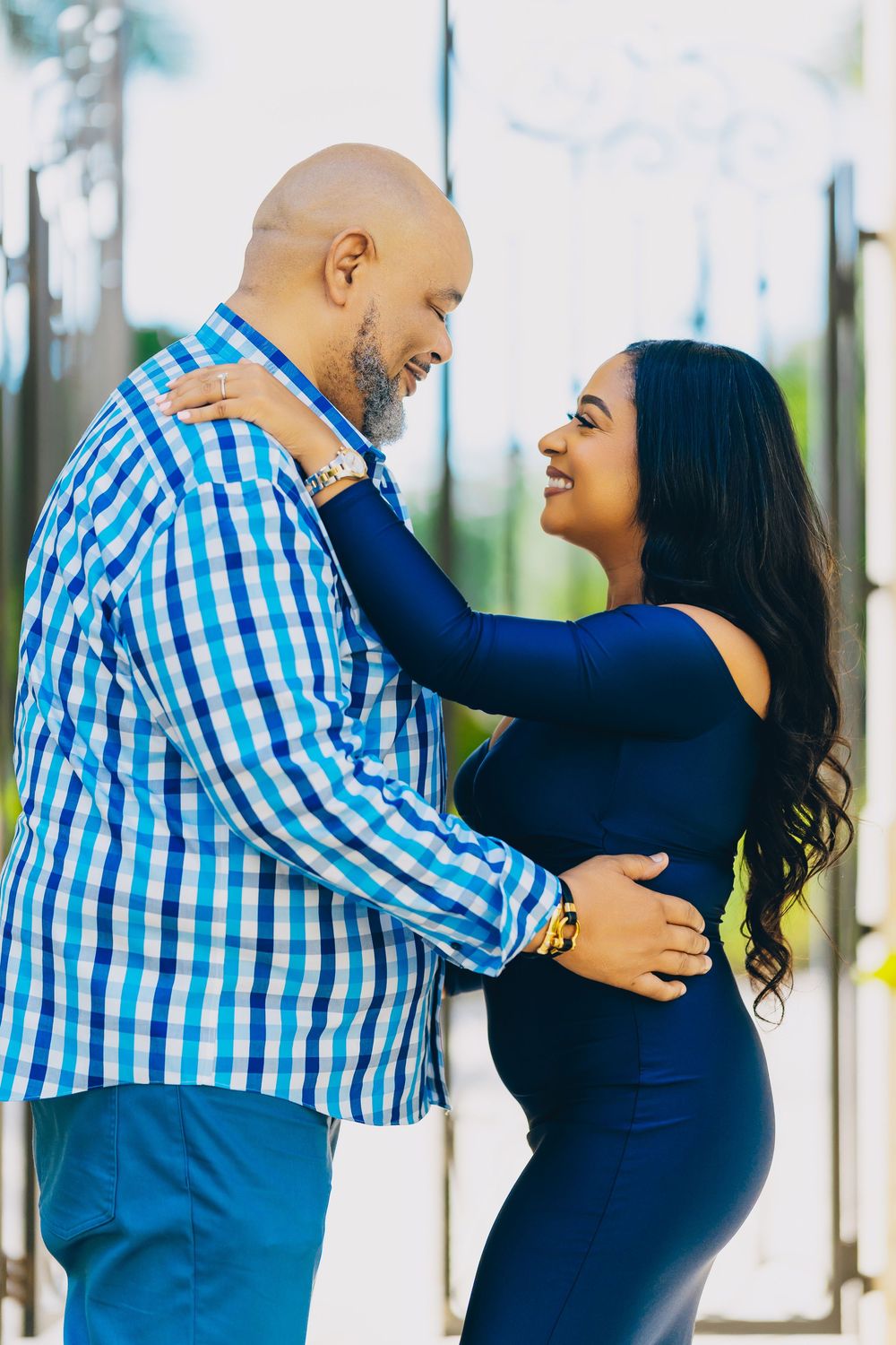 A couple embraces lovingly outdoors, with the person in navy blue and another in a blue checkered shirt.