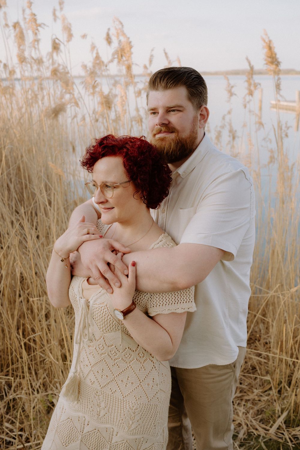 A romantic embrace among tall golden reeds at sunset with a warm vintage filter effect.