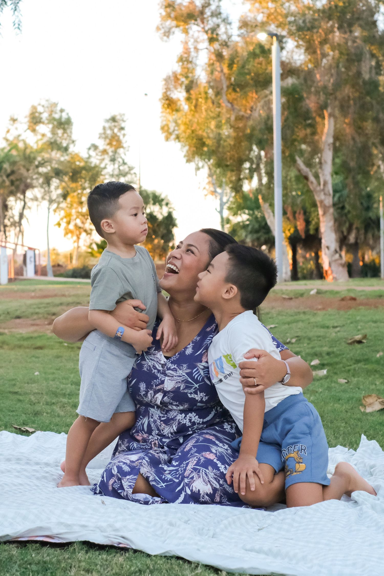 A playful family photo session on a white blanket surrounded by autumn trees.