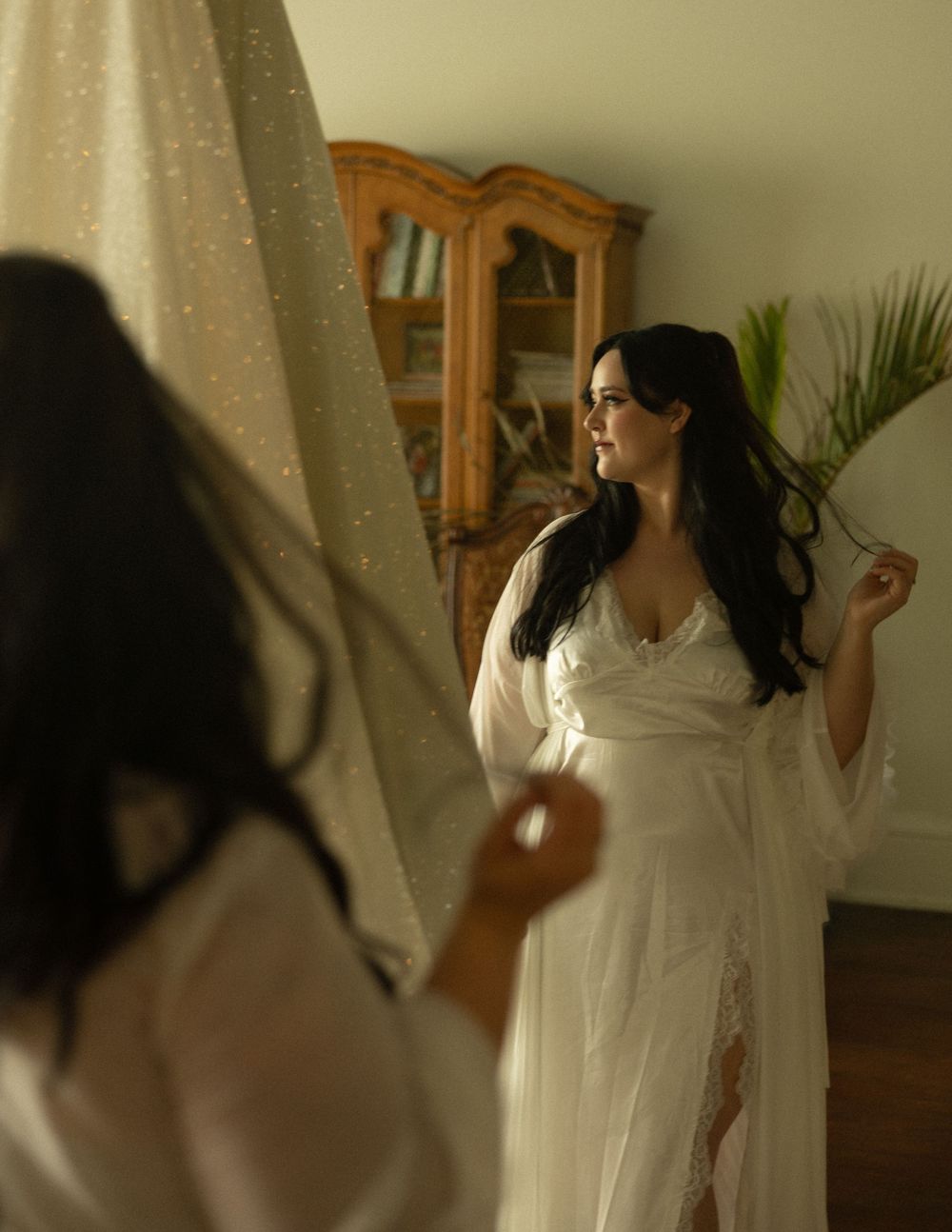 Wedding dress preparation scene with mirror reflection and warm lighting.