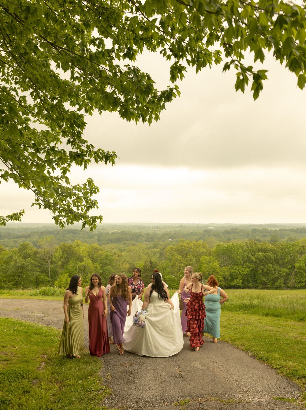 Group of wedding attendees gathered on hilltop path with scenic countryside view.