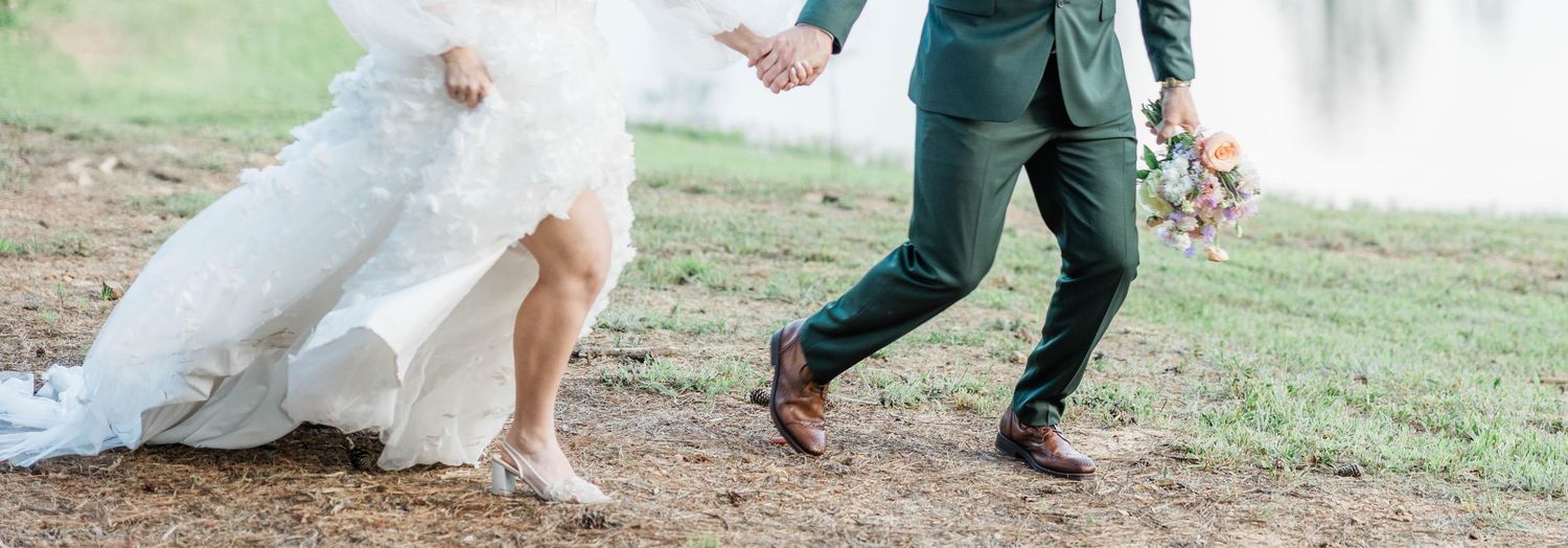 Close up of bride and groom's feet running on grassy slope.