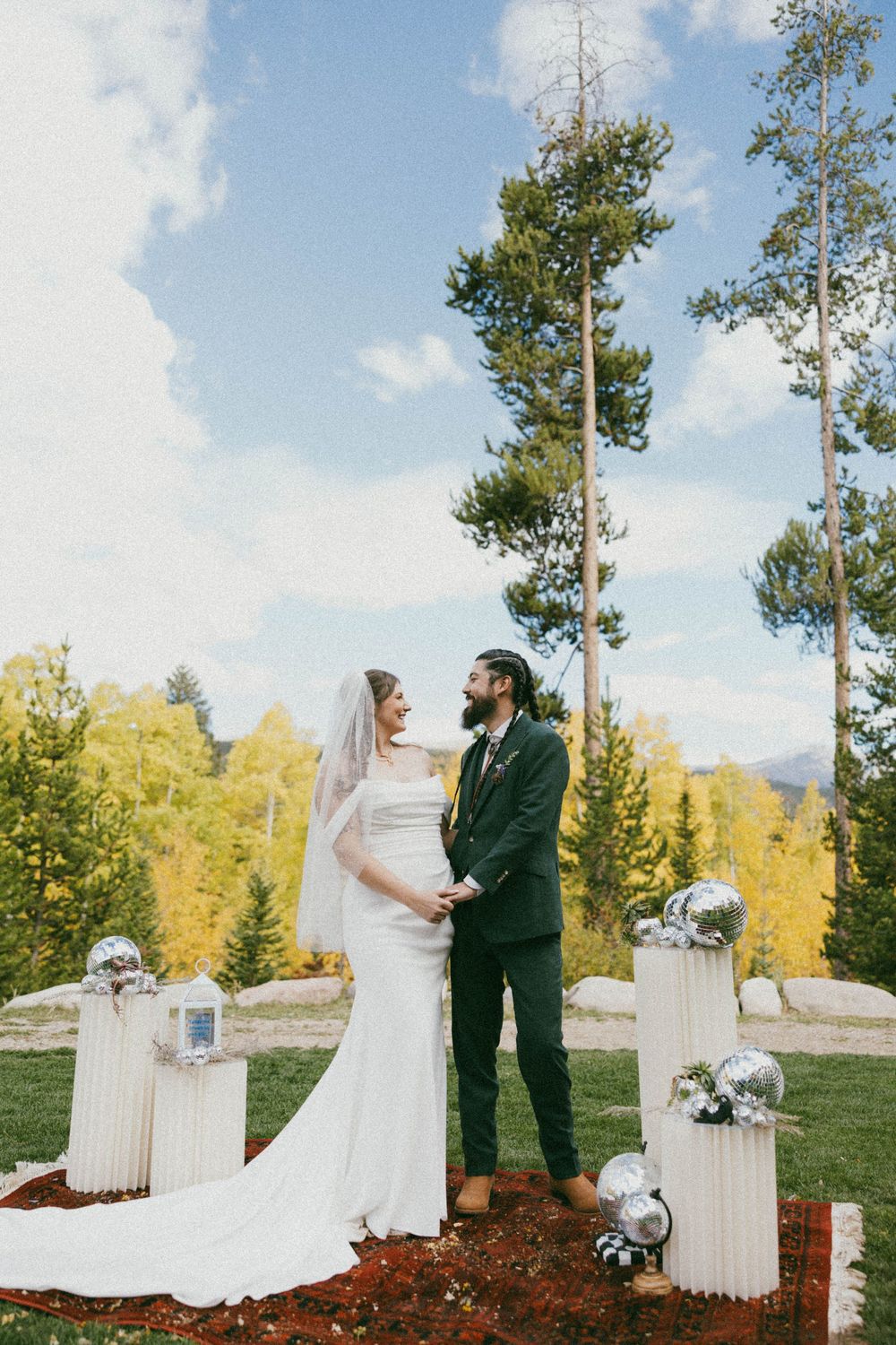 A romantic outdoor wedding ceremony set against golden autumn aspen trees and mountain scenery.