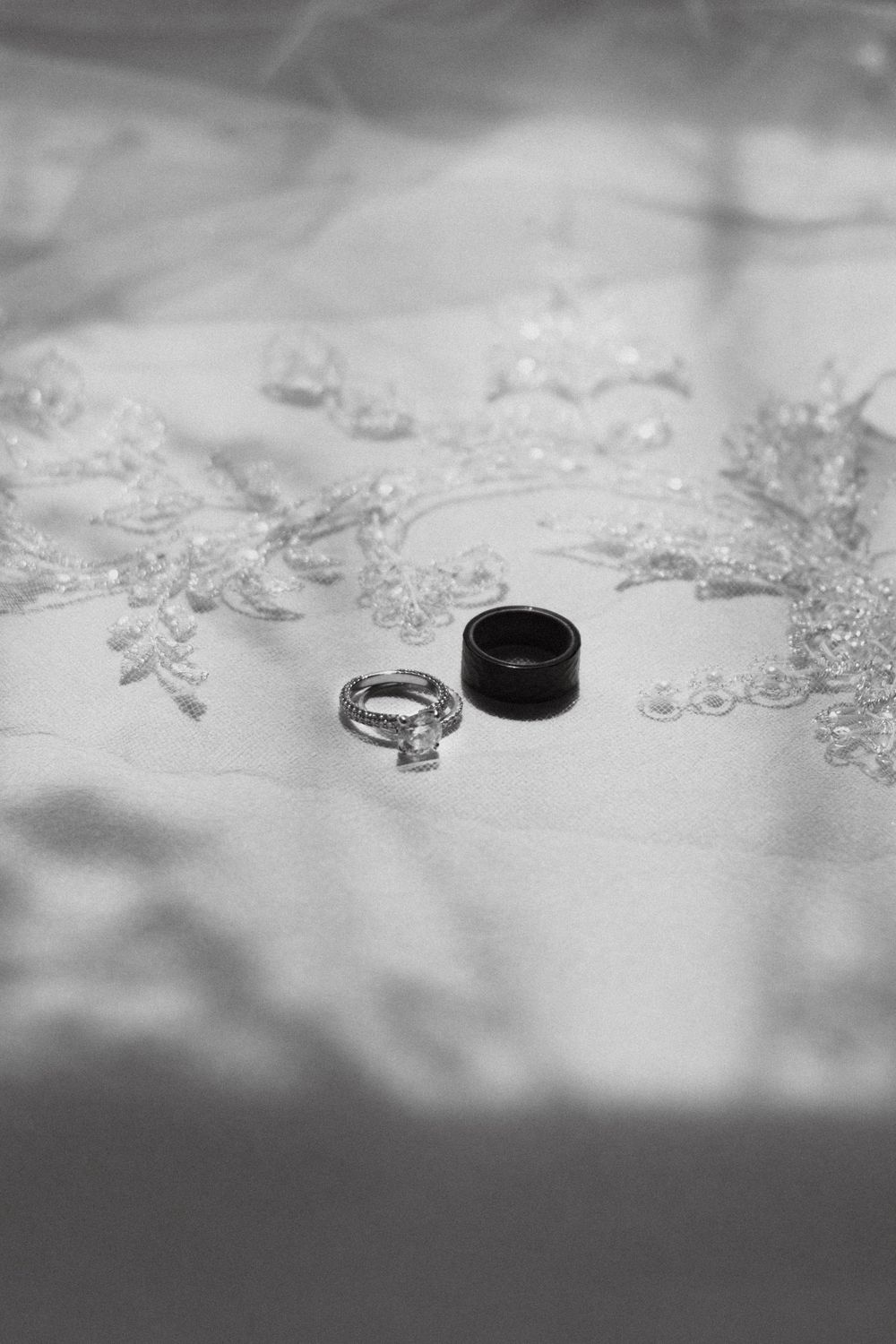 Close-up macro shot of wedding rings and scattered crystal decorations on a white textured surface.