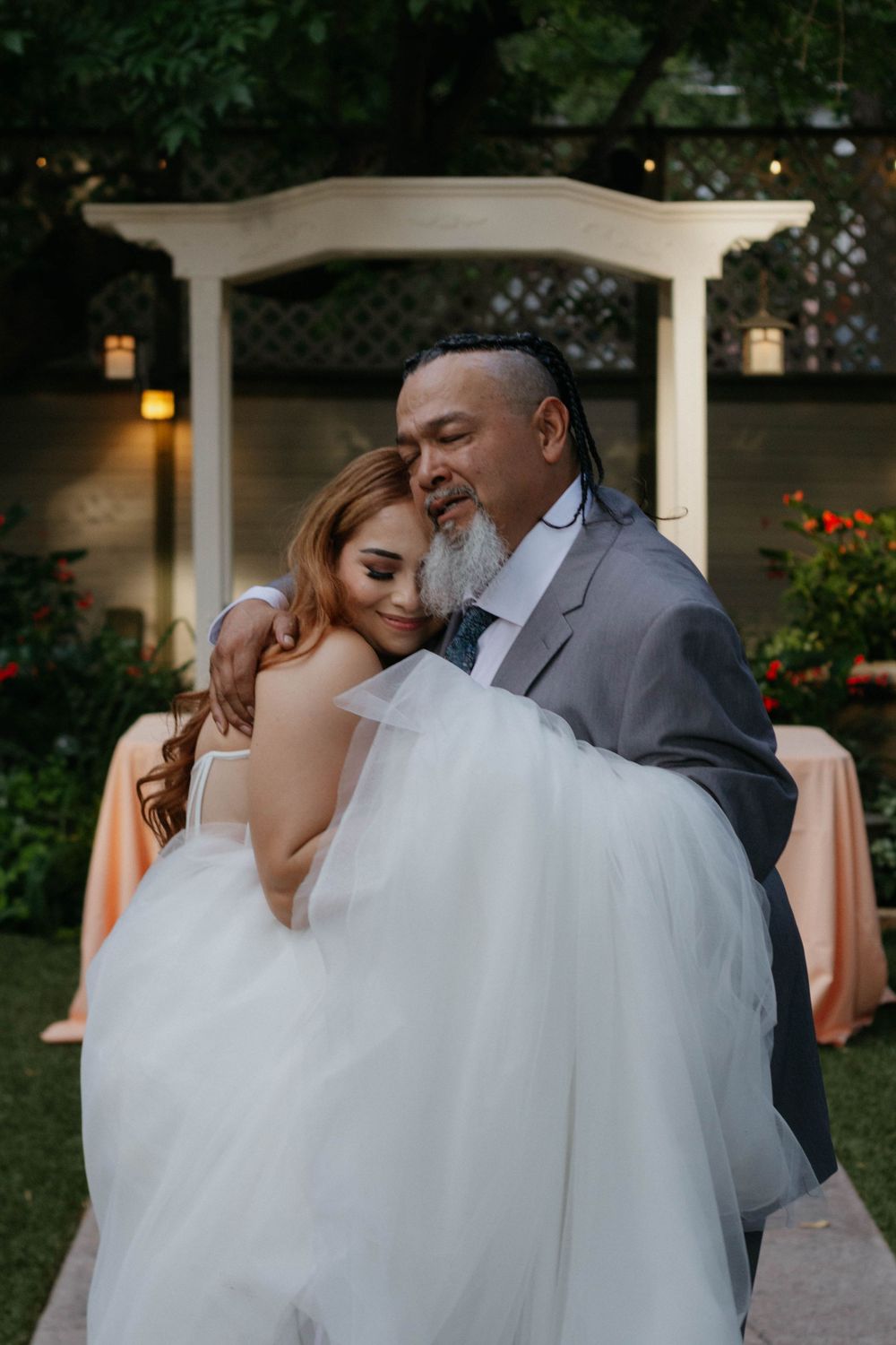 A romantic wedding couple shares intimate moments in an outdoor garden setting at sunset.
