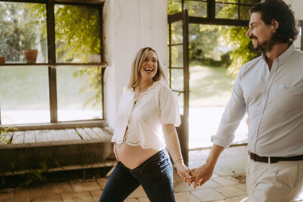 A couple shares joyful moments together by sunlit windows in an indoor setting.