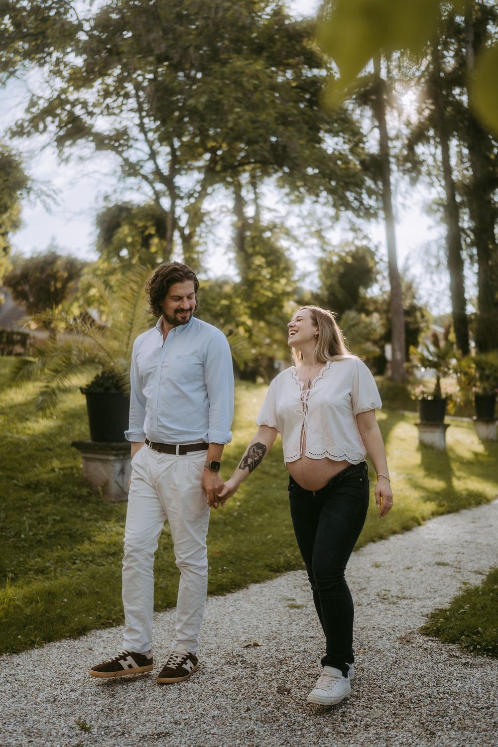 Two people walk together on a gravel path through a scenic wooded area.