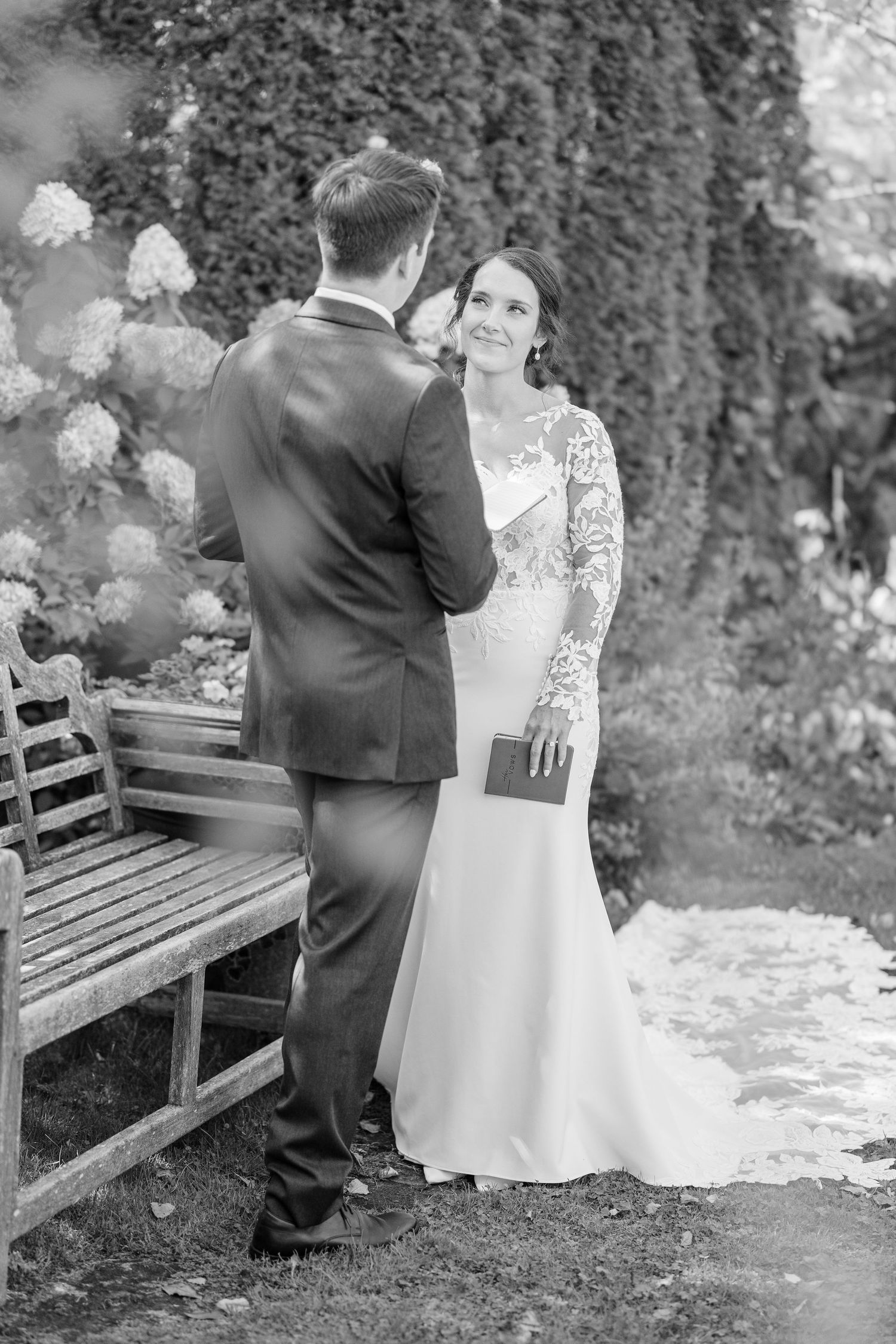 A romantic black and white sequence shows a couple in wedding attire sitting together on a garden bench.