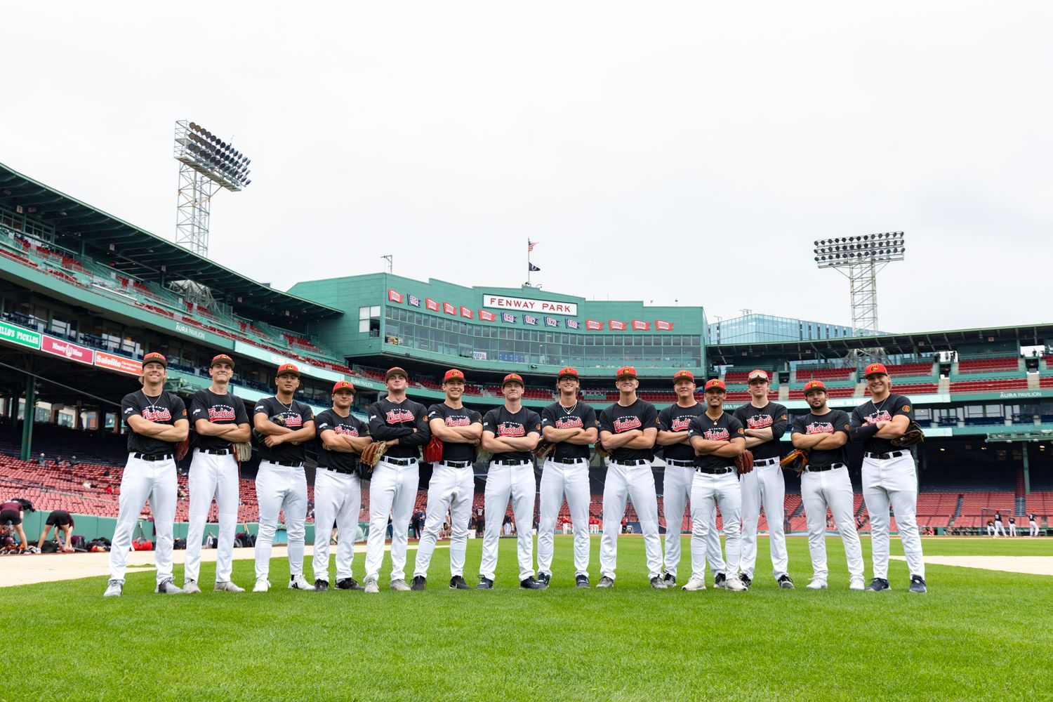 Orleans Firebirds baseball team stand on the greens at Fenway Park.