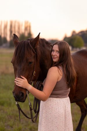 A tender moment between a horse and someone in a light dress during golden hour photography session.