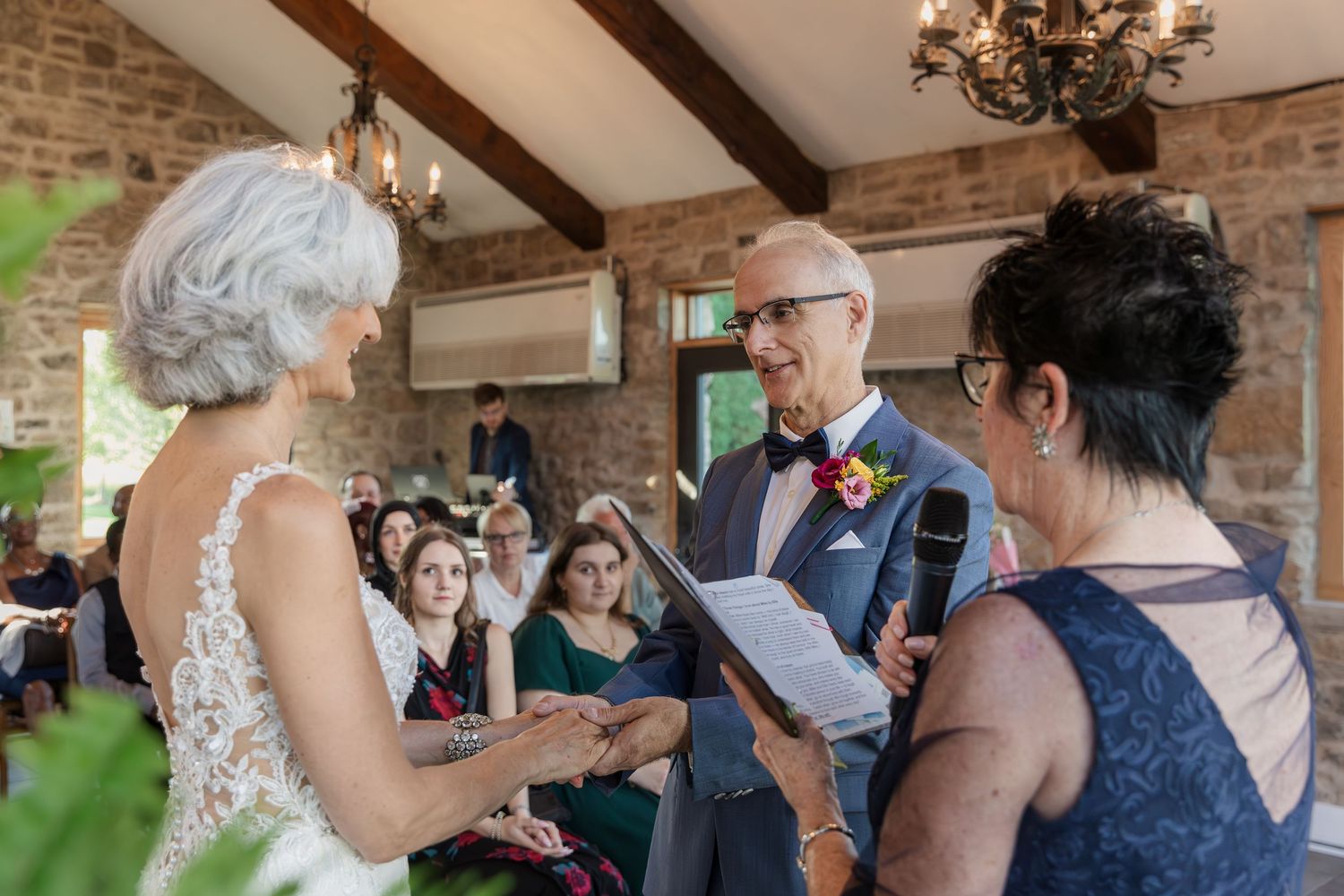Bride and groom hold hands in front of all their guests in the Carriage House at Vineland Estates Winery.