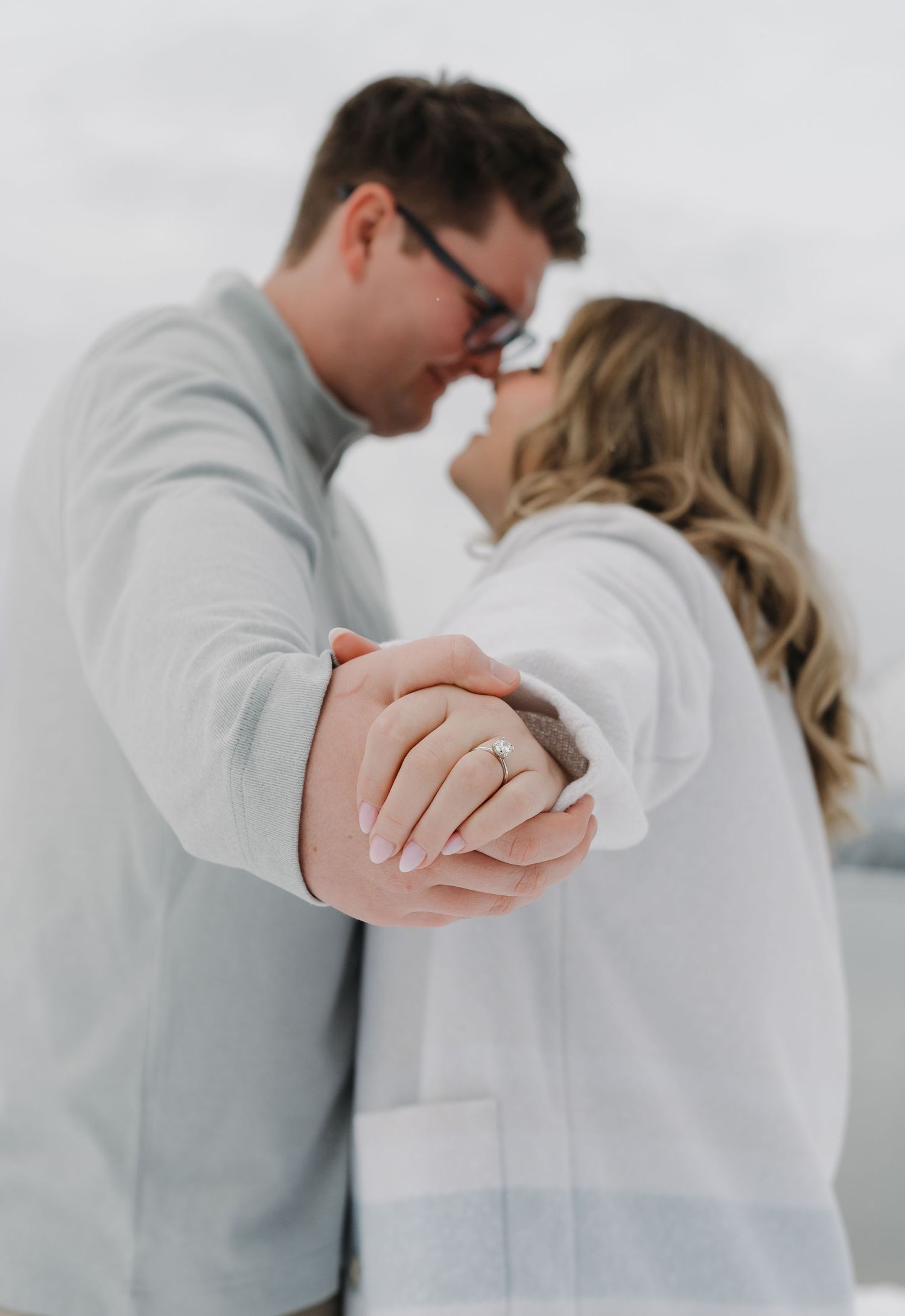 A romantic winter moment captured in soft focus as a couple embraces against a bright, snowy background. Leavenworth, WA