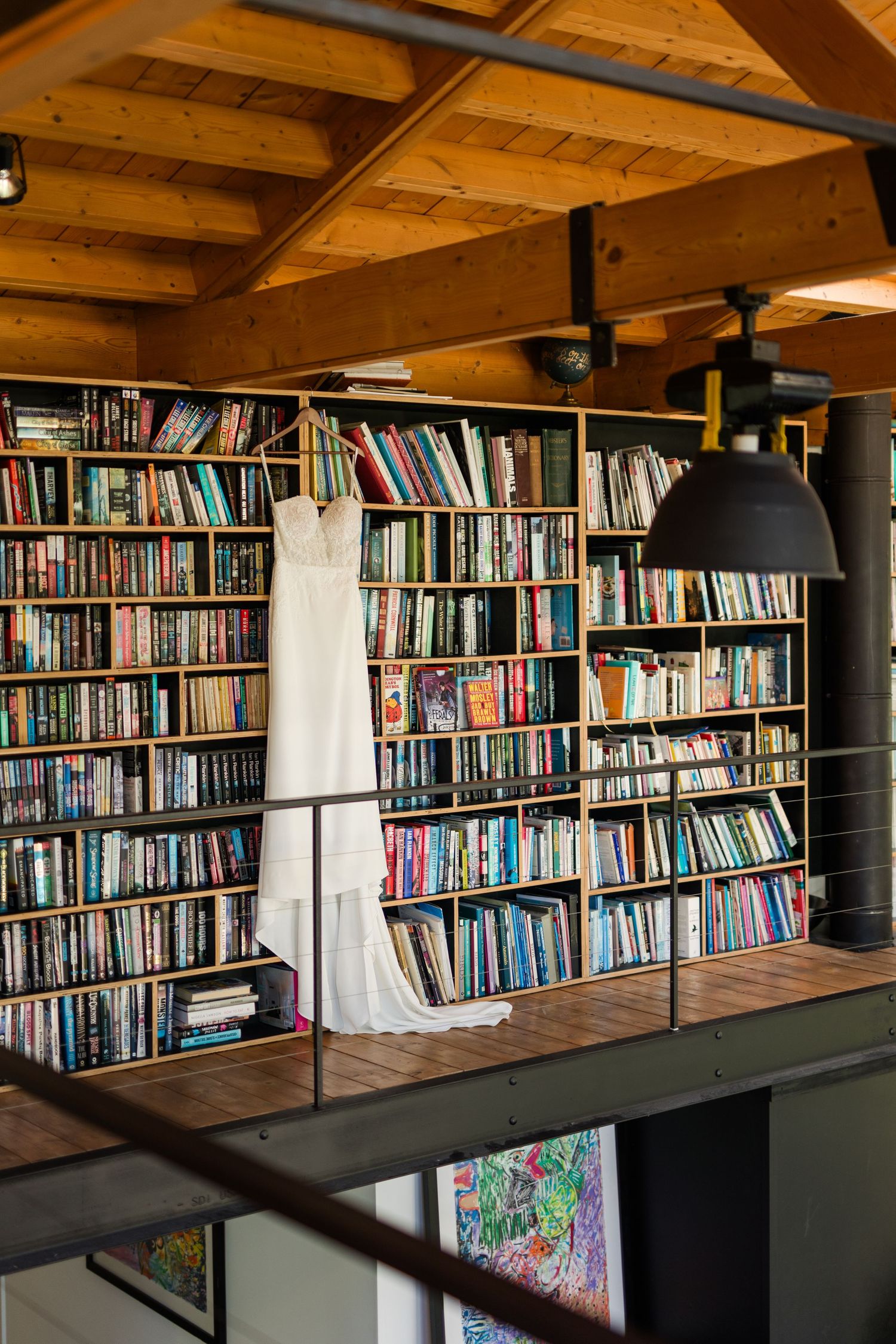 A panoramic view of wooden bookshelves filled with books under exposed wooden beams in a cozy library space.
