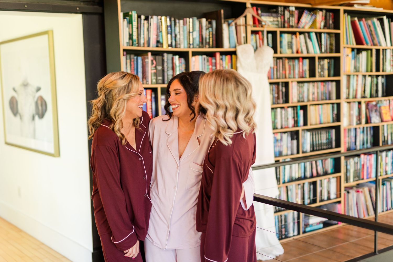 A group of people in burgundy blazers and white shirts stand in front of a library bookshelf.