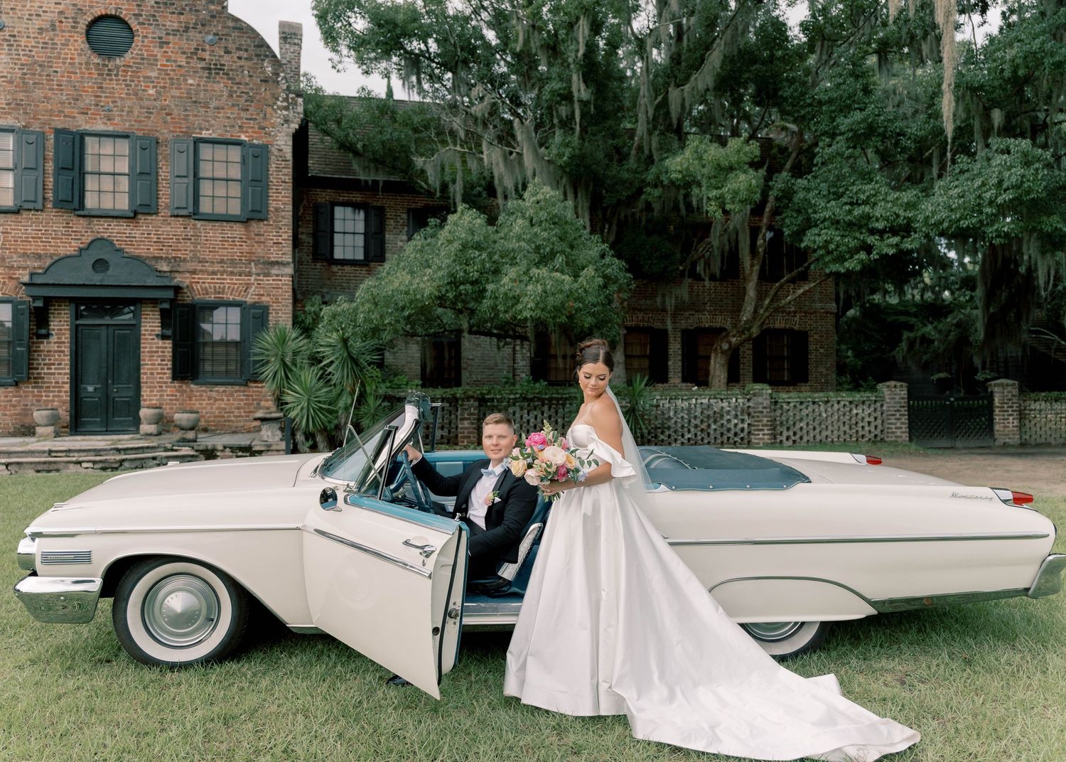 Wedding couple embracing near floral arrangements and decorative archway in garden setting.