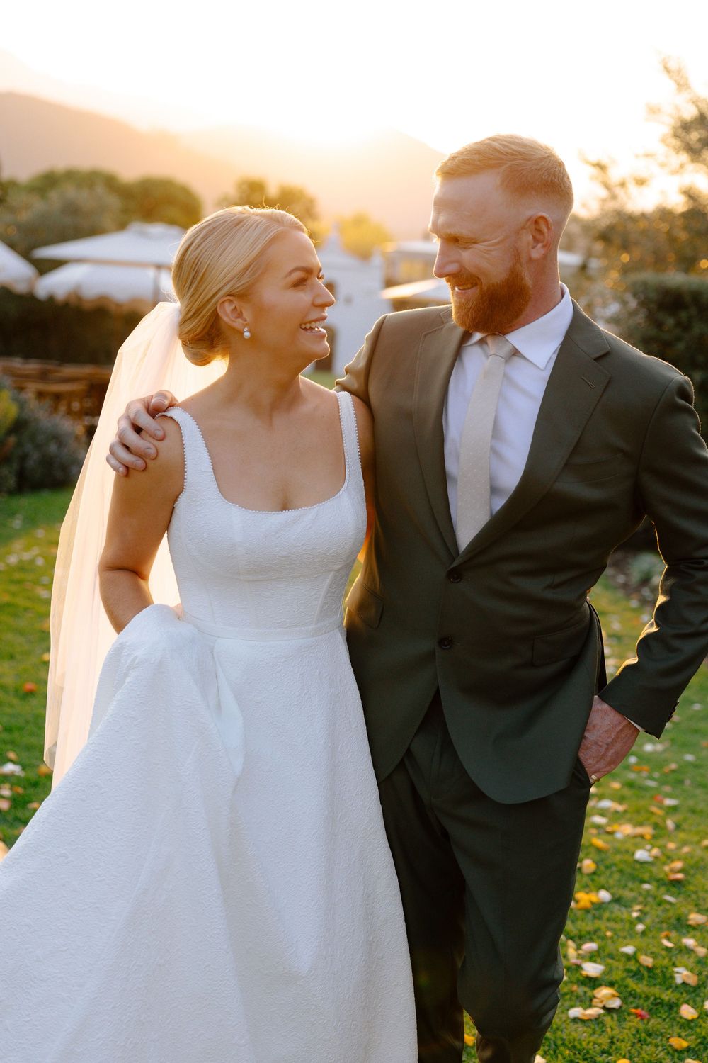 Newlyweds share intimate moments during sunset photo session in an autumn field with fallen leaves.