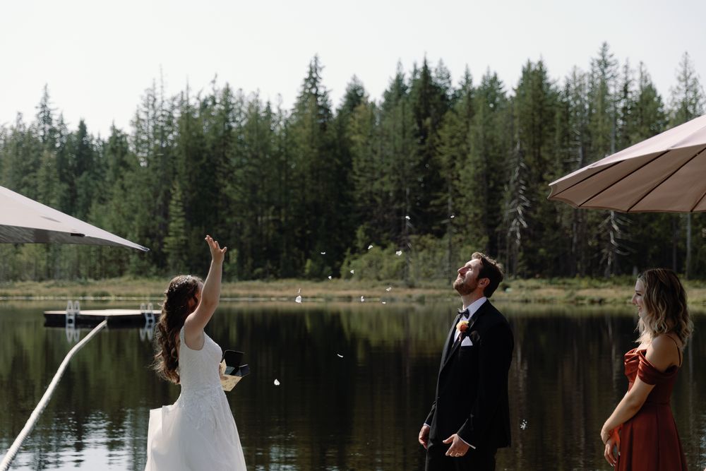 Bride throwing flower petals at her groom while on a dock at a Sunshine Coast wedding, taken by Kristina Harnett.