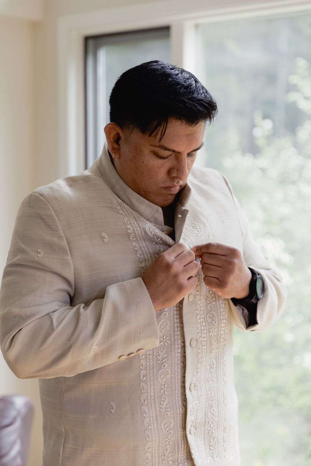A groom buttoning his shirt for his Okanagan wedding, taken by kristina Harnett.