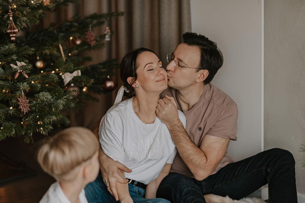 A couple shares tender moments together in a series of romantic photos near a Christmas tree.