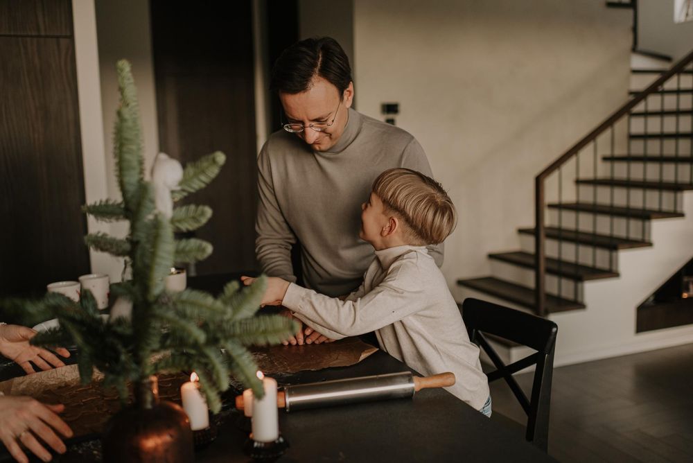 Couple in cozy home setting works together on laptop while sitting at dining table with coffee mugs nearby.