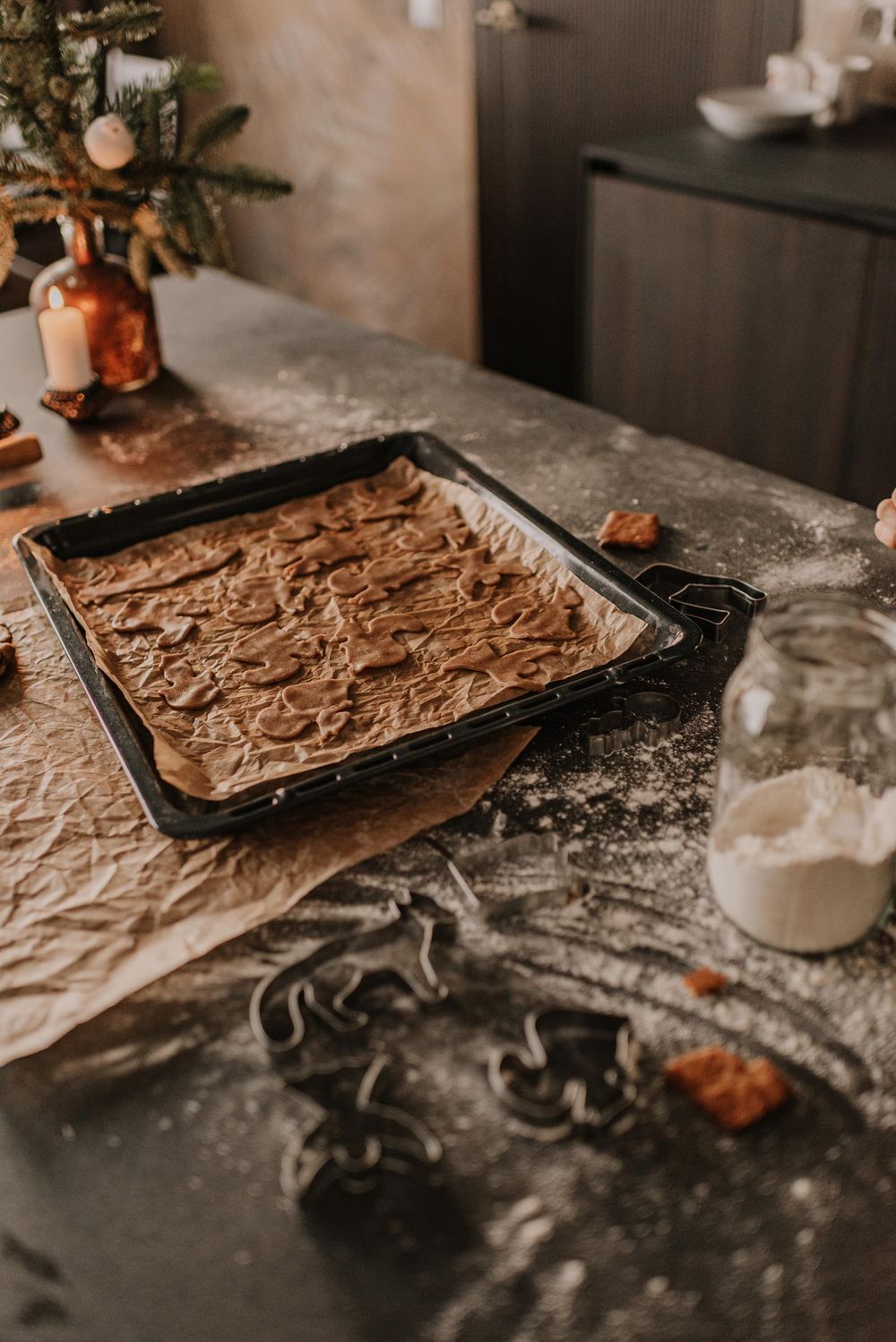 Four sequential photos showing chocolate cookie dough being spread onto a baking sheet on a floured surface in warm lighting.
