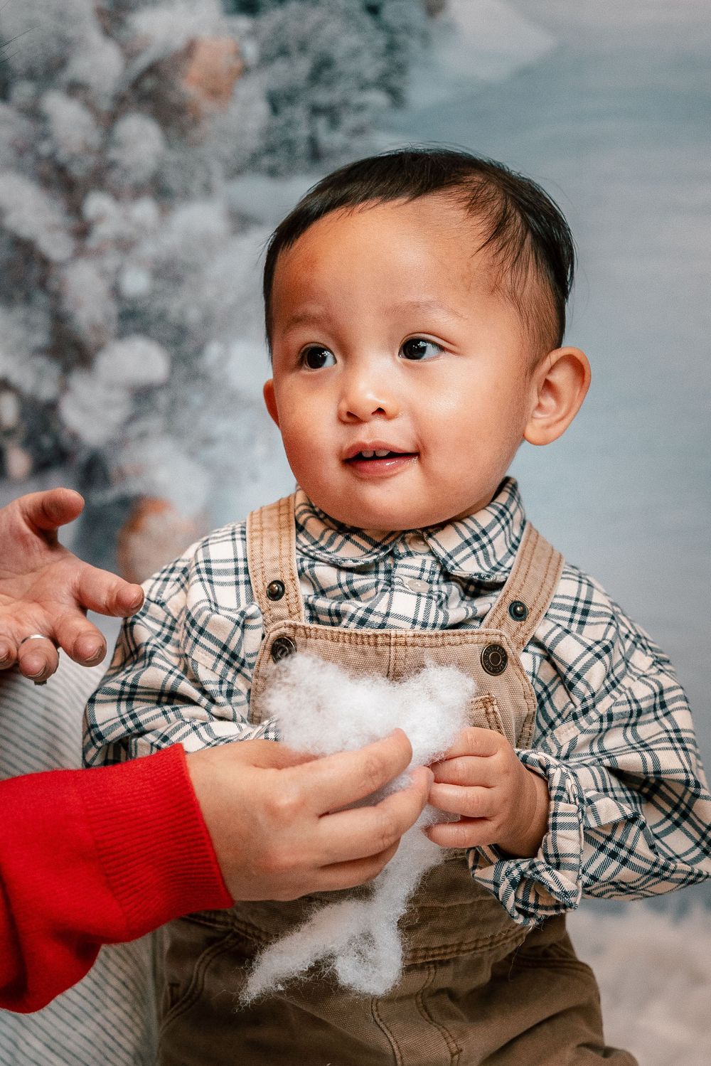 A sequence of photos showing a baby in plaid shirt playing with cotton-like snow in a winter studio setting.
