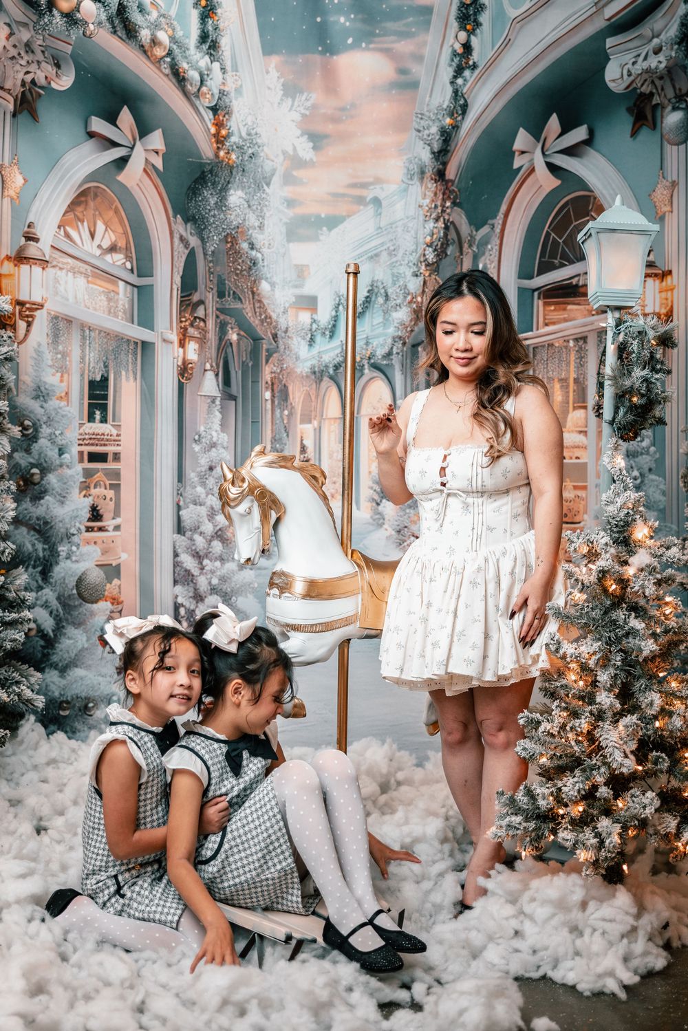 Dreamy holiday scene with white dress, rocking horse, and Christmas decorations in a whimsical blue archway setting.
