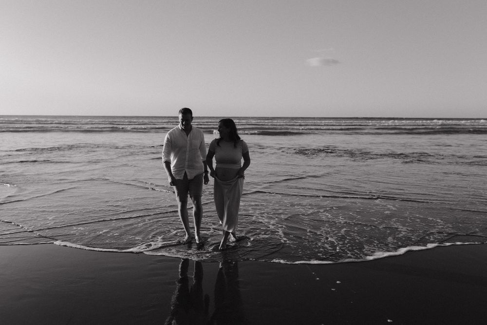 Black and white photo series showing people walking along a beach shoreline at sunset.