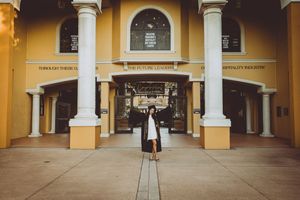 A symmetrical view of yellow Spanish colonial architecture with white columns and arched walkways at dusk.