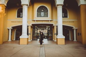 Yellow building exterior with white columns and arched walkway in panoramic view.