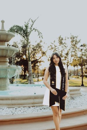 Graduation photos taken near an ornate fountain with blooming trees in the background.