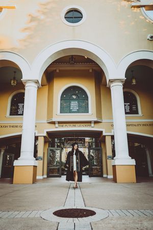 Symmetrical architectural shot of yellow building entrance with white columns and circular window.