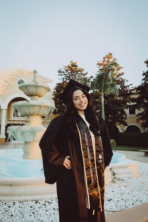 Graduation photos taken at a decorative fountain plaza with Spanish colonial architecture.