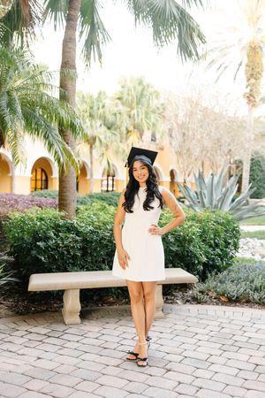 Graduation photoshoot in a tropical garden setting with palm trees and stone pathways.