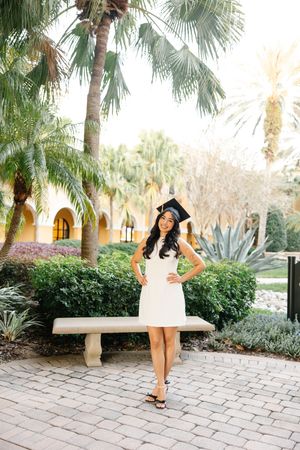 A graduation photoshoot sequence on a stone paved walkway surrounded by palm trees and tropical landscaping.