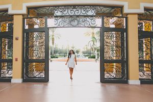 A panoramic view of an elegant hallway with ornate iron gates and yellow walls.