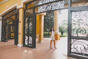 Ornate wrought iron gates and archways frame entrance to Mediterranean-style building.