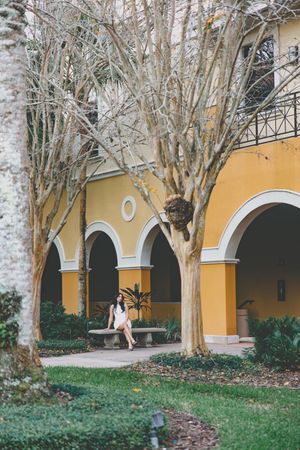 Yellow arched building with trees creates elegant walkway backdrop.