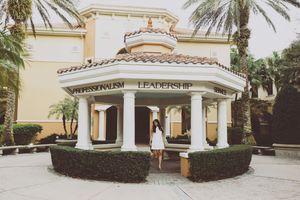 Exterior panorama of a Mediterranean-style building with palm trees and white columns.