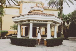 Elegant beige building facade with palm trees and Spanish colonial architecture.
