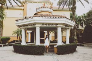 Mediterranean-style building exterior with palm trees and cream colored stucco walls.