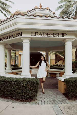 Graduation photos taken outside a building with white columns and leadership signage.