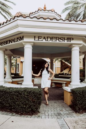 Series of playful graduation portraits in front of a Mediterranean-style building entrance.
