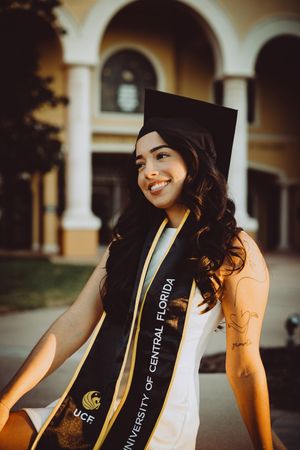Graduation photo featuring academic stoles and cap against classical architecture.