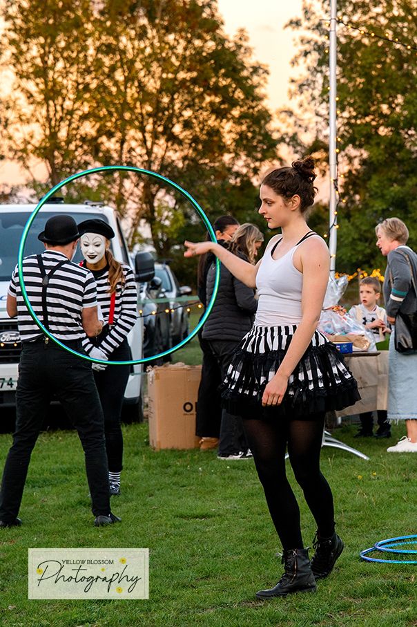 People practicing with colorful hula hoops on a grassy field during a circus workshop at sunset.