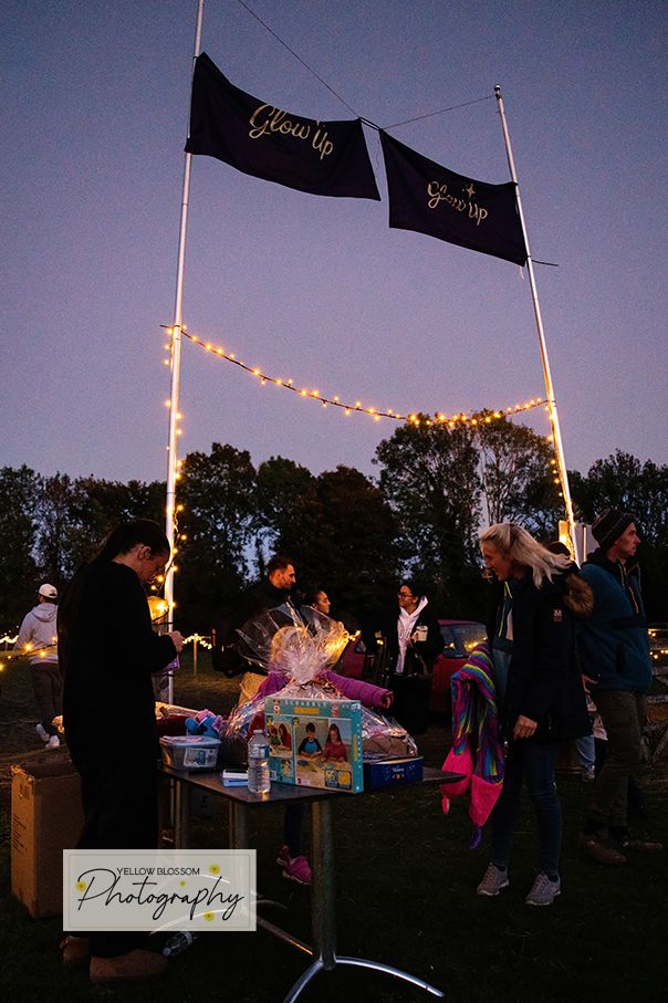 A series of outdoor evening photos showing a vendor booth with string lights and flags at a twilight gathering.