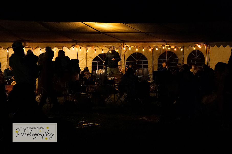 A romantic outdoor wedding reception tent glows warmly at dusk with string lights creating an enchanting atmosphere.