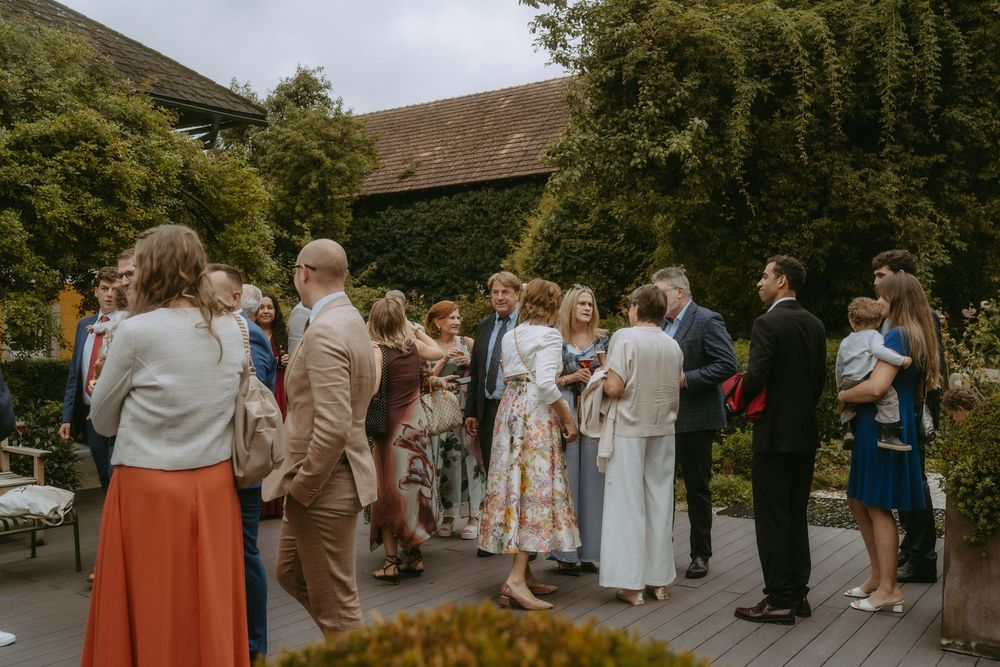 Wedding guests mingling outdoors at garden reception.