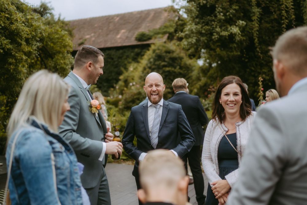 Casual outdoor gathering of wedding guests in garden setting.